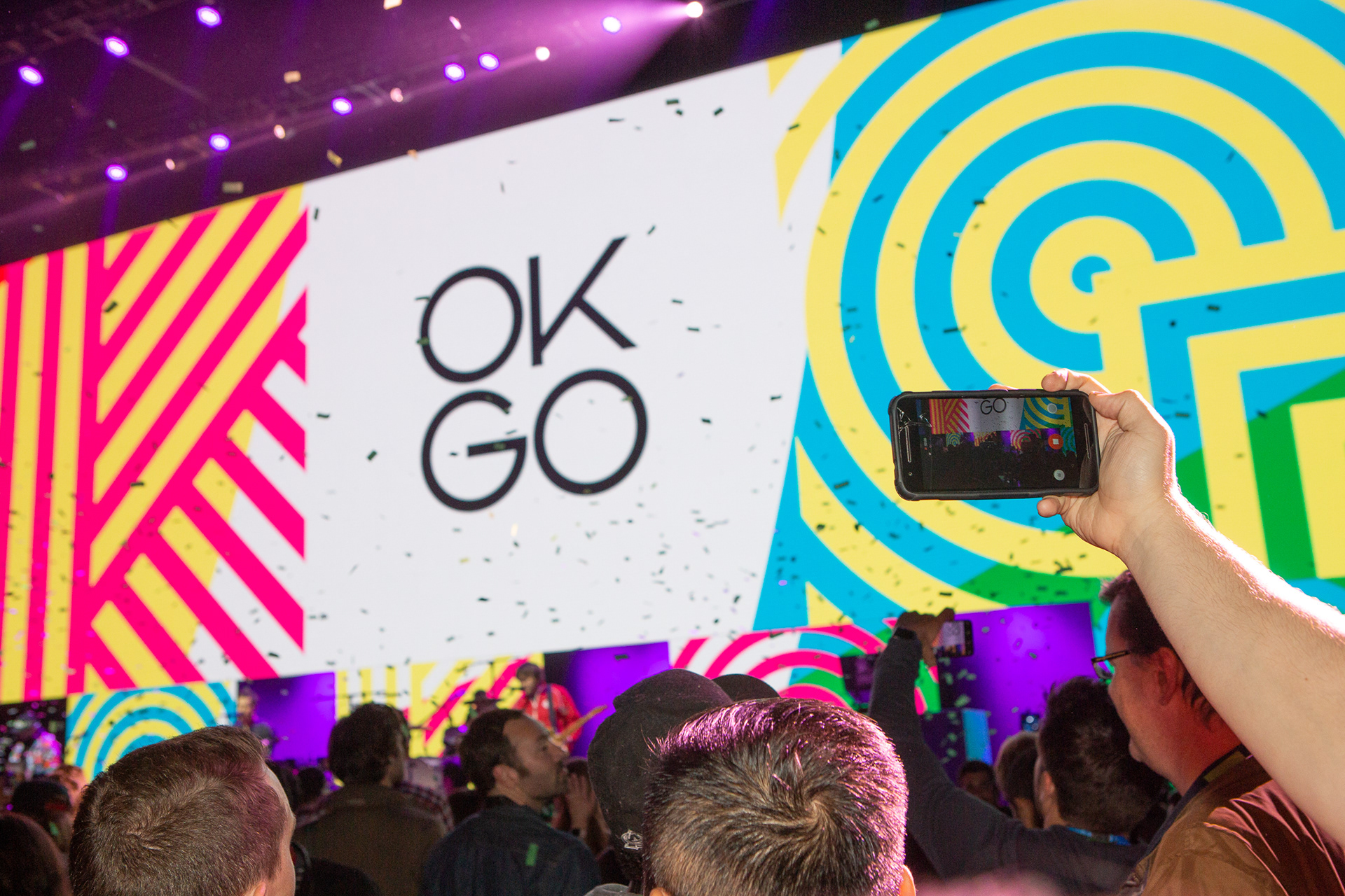 Audience member filming OK Go performance on phone with colorful LED screens